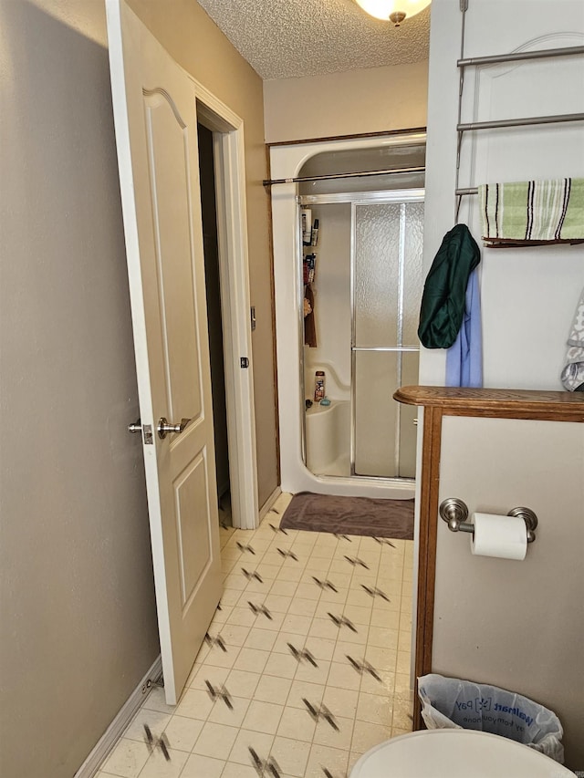 bathroom featuring tile patterned flooring, a textured ceiling, and a stall shower