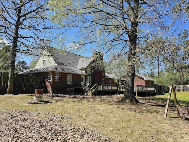 exterior space with brick siding, fence, a deck, and a chimney