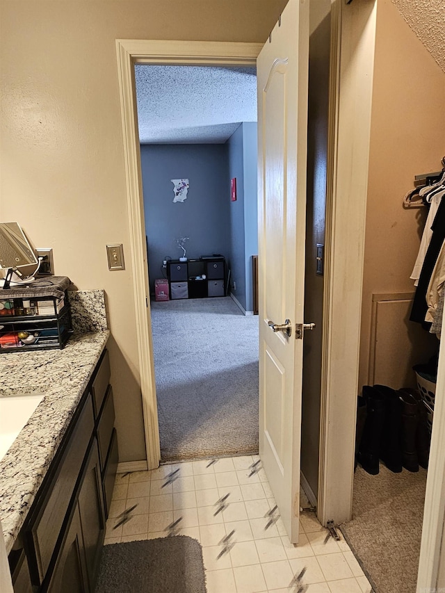 bathroom with a textured ceiling, vanity, and baseboards