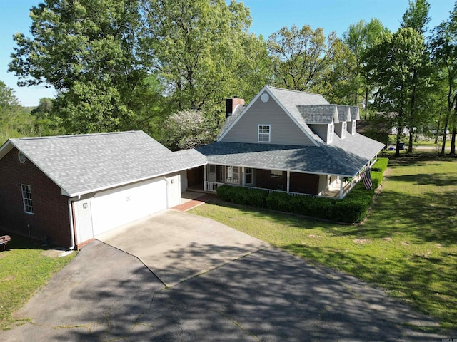 view of front of home featuring an attached garage, covered porch, a chimney, a front lawn, and driveway