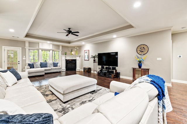 living room with ornamental molding, ceiling fan, a raised ceiling, and wood finished floors