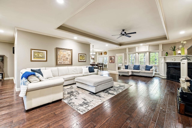 living room featuring a fireplace, ornamental molding, a ceiling fan, hardwood / wood-style floors, and a raised ceiling