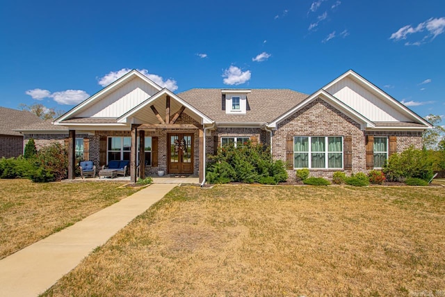 craftsman house featuring french doors, a front yard, and brick siding
