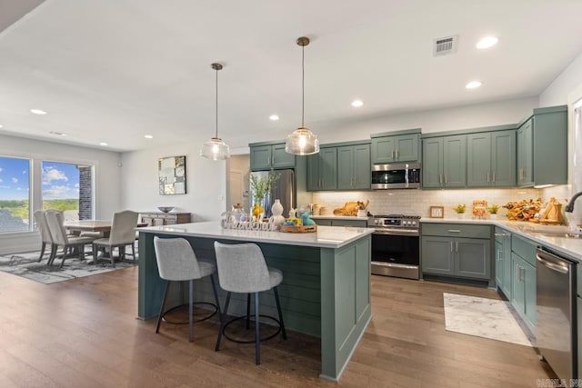 kitchen featuring green cabinets, dark wood-style floors, light countertops, decorative backsplash, and stainless steel appliances