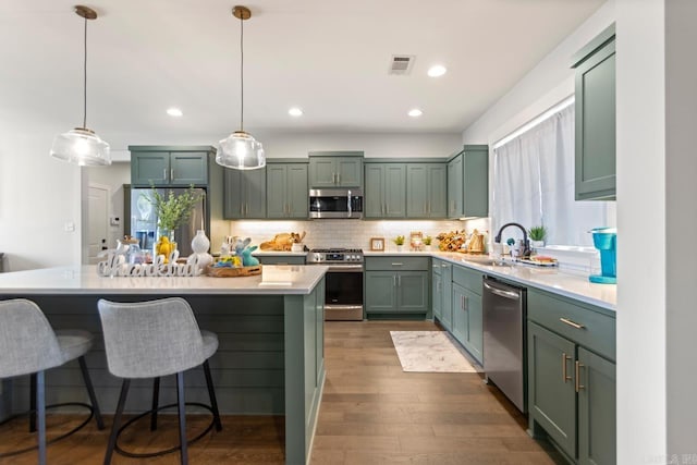 kitchen with green cabinets, visible vents, appliances with stainless steel finishes, and a sink