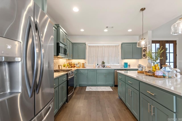 kitchen featuring light countertops, appliances with stainless steel finishes, a sink, and green cabinetry
