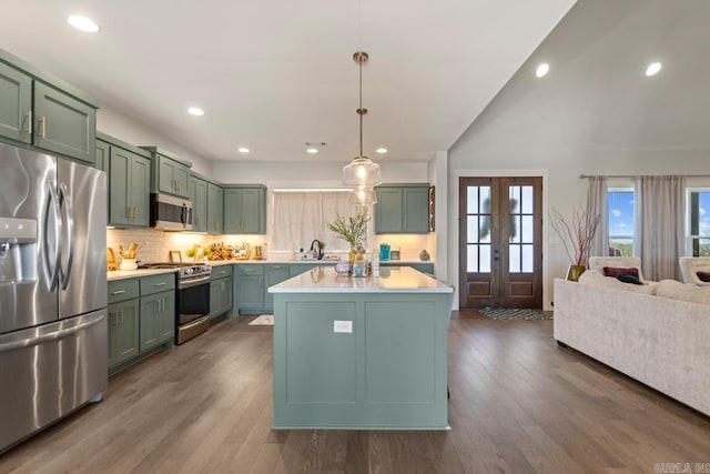 kitchen featuring tasteful backsplash, light countertops, stainless steel appliances, dark wood-style floors, and green cabinetry