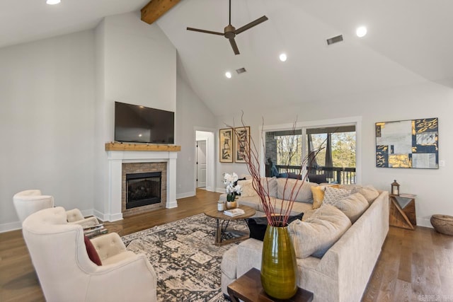 living area featuring a glass covered fireplace, baseboards, a ceiling fan, beam ceiling, and high vaulted ceiling