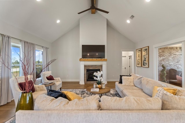 living room with ceiling fan, high vaulted ceiling, a fireplace, visible vents, and baseboards