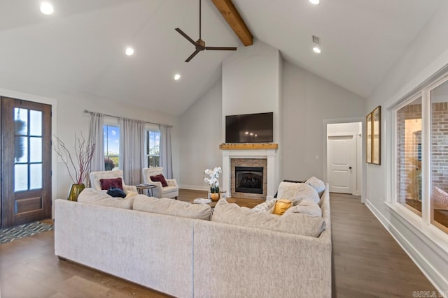 living area with ceiling fan, high vaulted ceiling, beamed ceiling, a fireplace, and baseboards