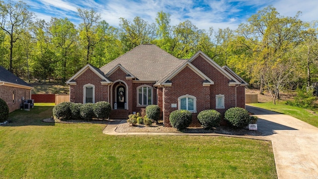 view of front of home featuring concrete driveway, brick siding, fence, and a front lawn