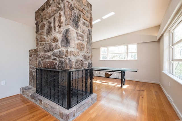details with wood finished floors, baseboards, and a stone fireplace
