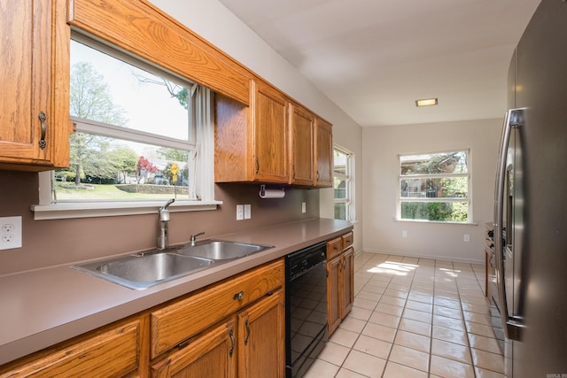 kitchen with freestanding refrigerator, black dishwasher, light tile patterned flooring, a sink, and plenty of natural light