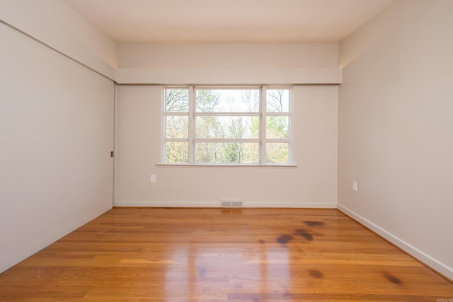 spare room with wood finished floors, baseboards, and visible vents