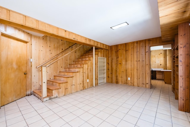 unfurnished living room featuring stairs and wooden walls
