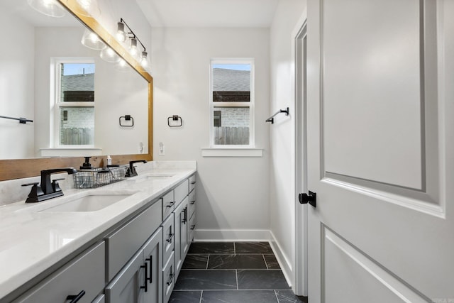 bathroom with double vanity, marble finish floor, a sink, and baseboards
