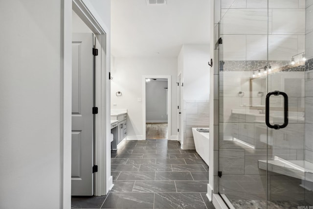 bathroom with a soaking tub, vanity, visible vents, a stall shower, and baseboards