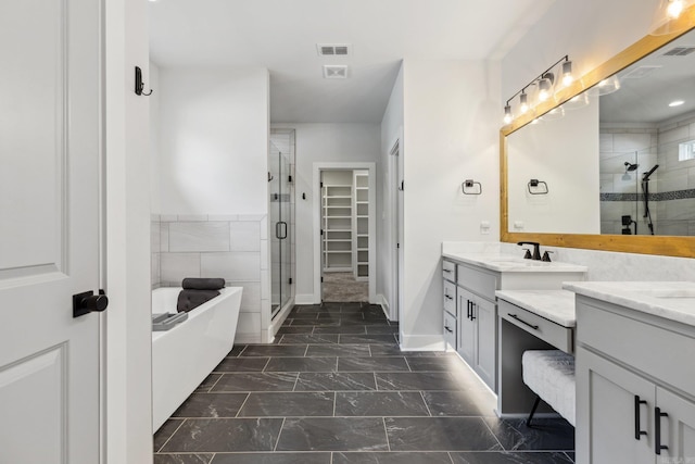 bathroom with a shower stall, two vanities, a freestanding bath, and a sink