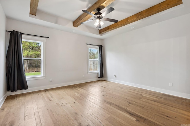 empty room with light wood-style flooring, a ceiling fan, beam ceiling, and plenty of natural light