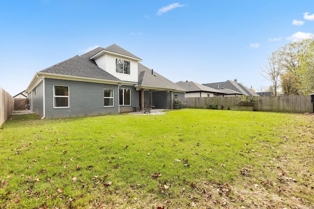 rear view of property featuring a yard, a fenced backyard, brick siding, and roof with shingles
