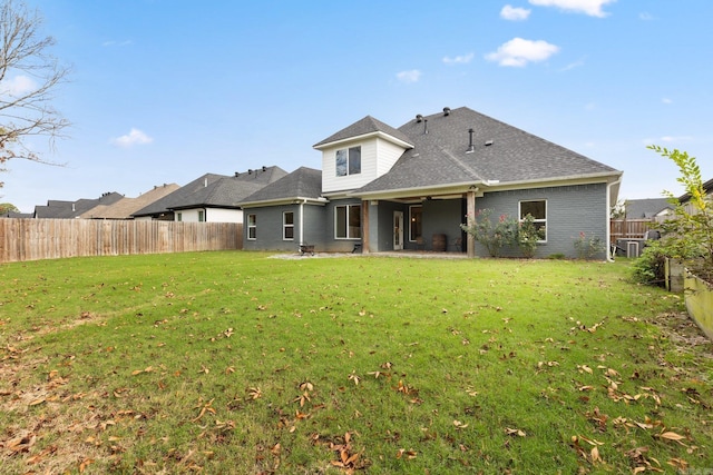 back of property with a patio, a yard, a fenced backyard, and roof with shingles