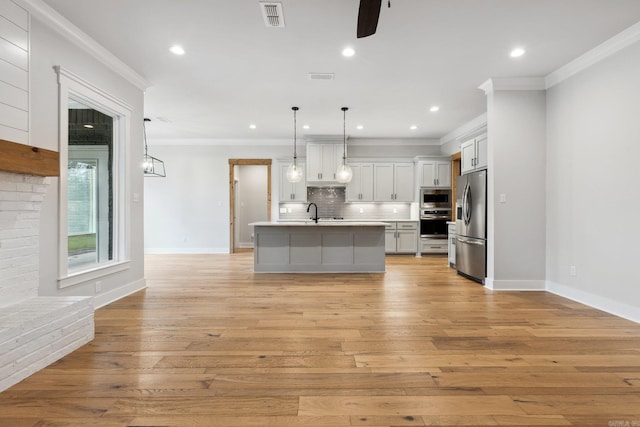kitchen with light wood-style floors, visible vents, light countertops, stainless steel appliances, and backsplash