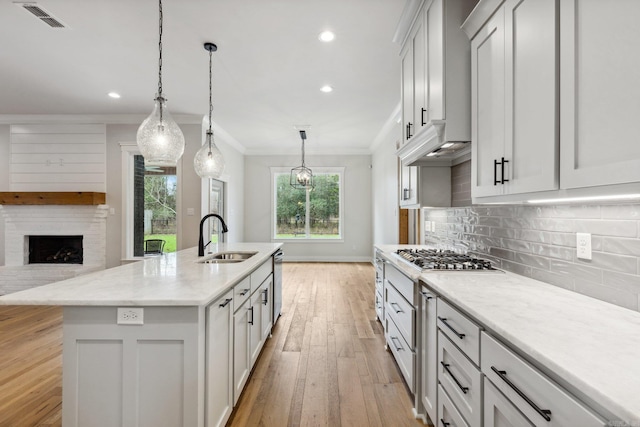 kitchen featuring tasteful backsplash, visible vents, stainless steel appliances, light wood finished floors, and a sink