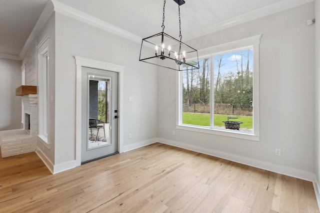 unfurnished dining area featuring crown molding, baseboards, light wood-type flooring, and a notable chandelier