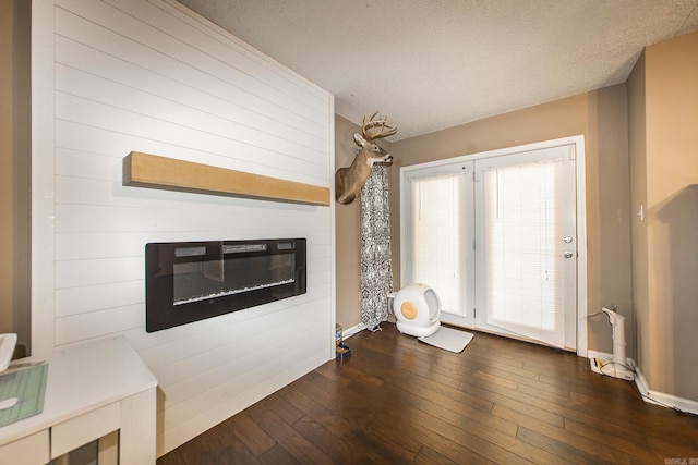 unfurnished living room featuring a glass covered fireplace, baseboards, and dark wood finished floors