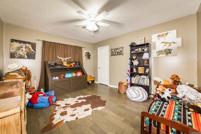 interior space with a textured ceiling, wood finished floors, ceiling fan, and baseboards