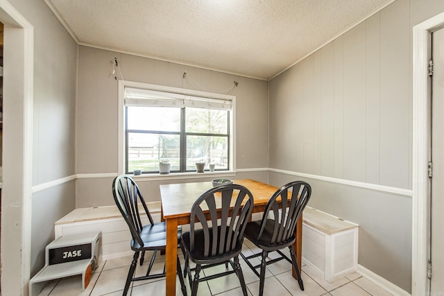 dining room featuring crown molding, light tile patterned floors, and a textured ceiling