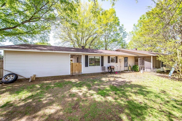 view of front of home featuring a sunroom, fence, and a front lawn