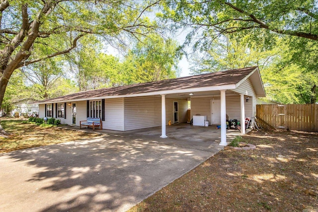 view of front of home featuring concrete driveway, a carport, and fence