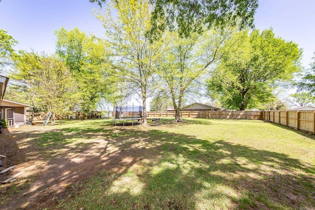 view of yard with a trampoline and a fenced backyard