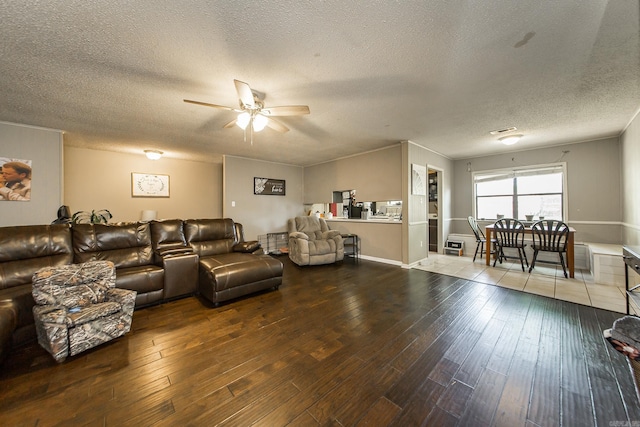 living room featuring wood-type flooring, ceiling fan, and a textured ceiling