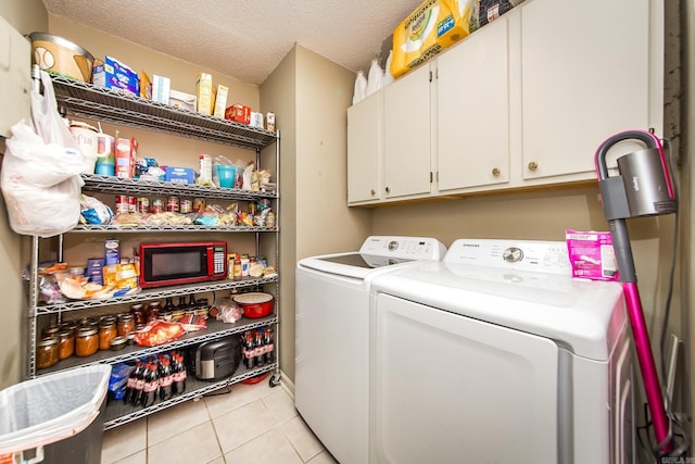 laundry room with light tile patterned floors, washing machine and dryer, a textured ceiling, and cabinet space