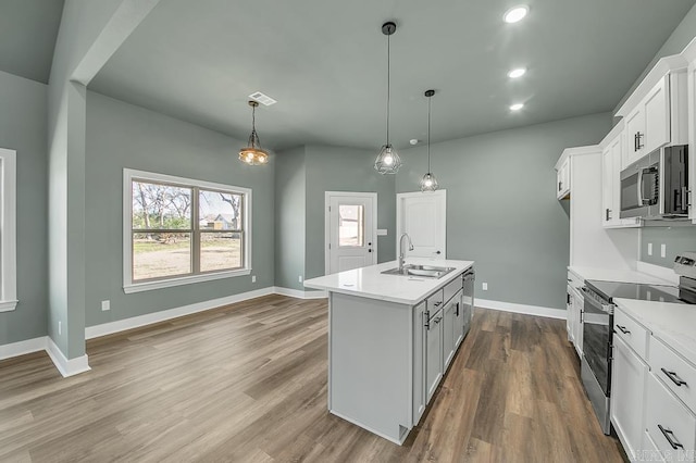 kitchen featuring dark wood-style flooring, an island with sink, light countertops, appliances with stainless steel finishes, and a sink