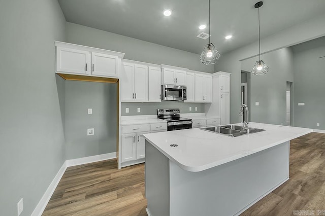 kitchen featuring visible vents, a sink, appliances with stainless steel finishes, a kitchen island with sink, and white cabinetry