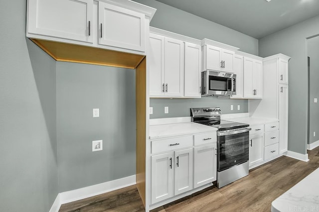 kitchen featuring dark wood-type flooring, light countertops, baseboards, and stainless steel appliances