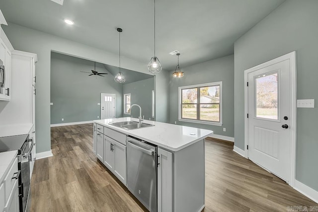 kitchen with dark wood finished floors, a kitchen island with sink, light countertops, a sink, and stainless steel appliances