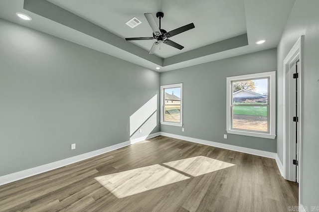 unfurnished room with a raised ceiling, dark wood-type flooring, baseboards, and recessed lighting