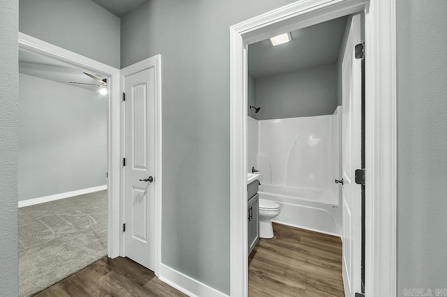 full bath with toilet, a ceiling fan, vanity, wood finished floors, and bathing tub / shower combination