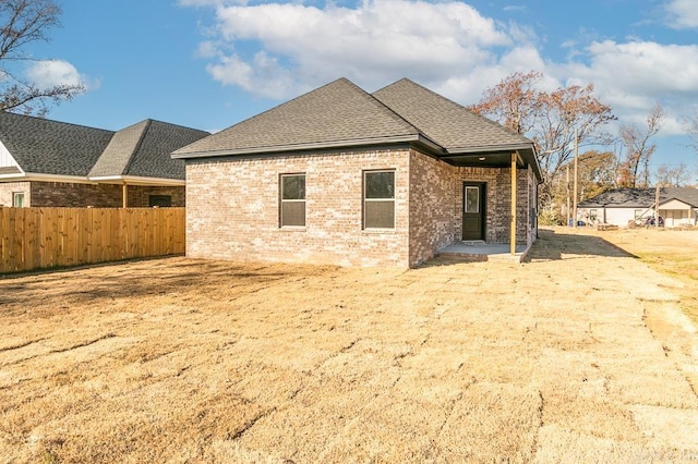 back of house featuring a patio, brick siding, fence, and a shingled roof