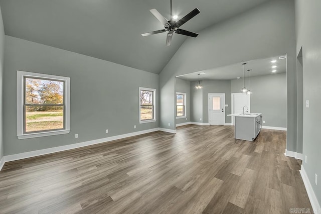 unfurnished living room featuring a sink, dark wood finished floors, high vaulted ceiling, and a healthy amount of sunlight