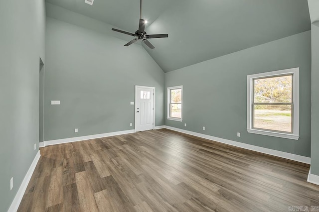 empty room featuring high vaulted ceiling, dark wood-type flooring, baseboards, and ceiling fan
