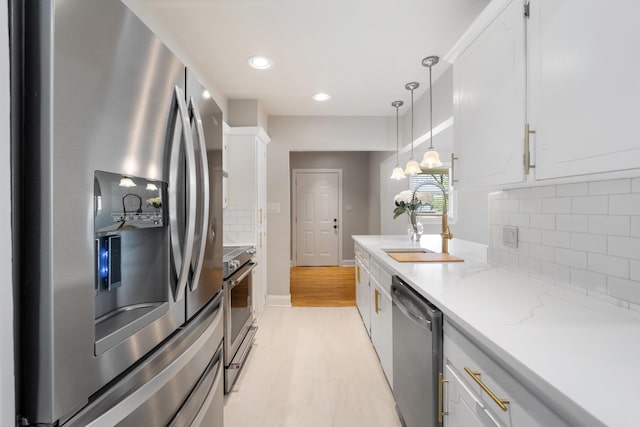 6723 Greenwood, Little Rock, AR 72207 - kitchen featuring hanging light fixtures, tasteful backsplash, stainless steel appliances, and white cabinetry