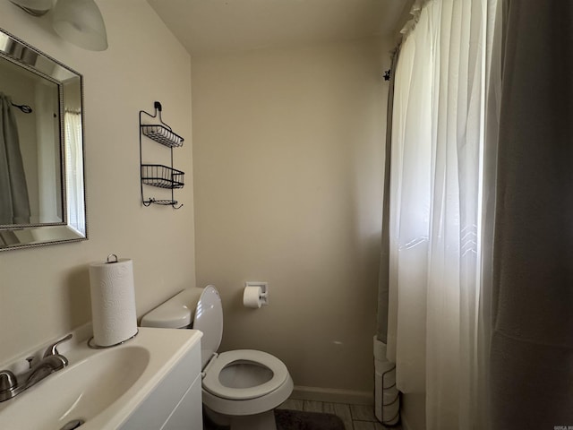 bathroom featuring baseboards, a sink, and toilet