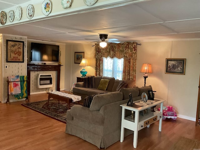 living area with baseboards, a ceiling fan, heating unit, and wood finished floors