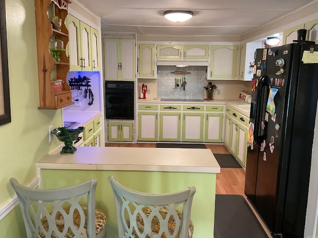 kitchen featuring tasteful backsplash, a peninsula, light countertops, open shelves, and black appliances