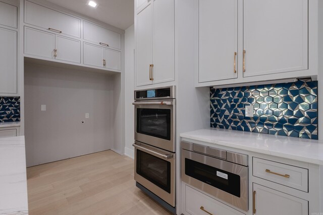 221 Abington Cir, Little Rock, AR 72223 - kitchen featuring light stone countertops, decorative backsplash, white cabinetry, stainless steel appliances, and light wood finished floors